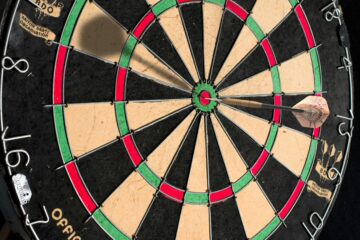 round concentric circles of a dart board with a dart in the middle circle