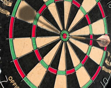 round concentric circles of a dart board with a dart in the middle circle