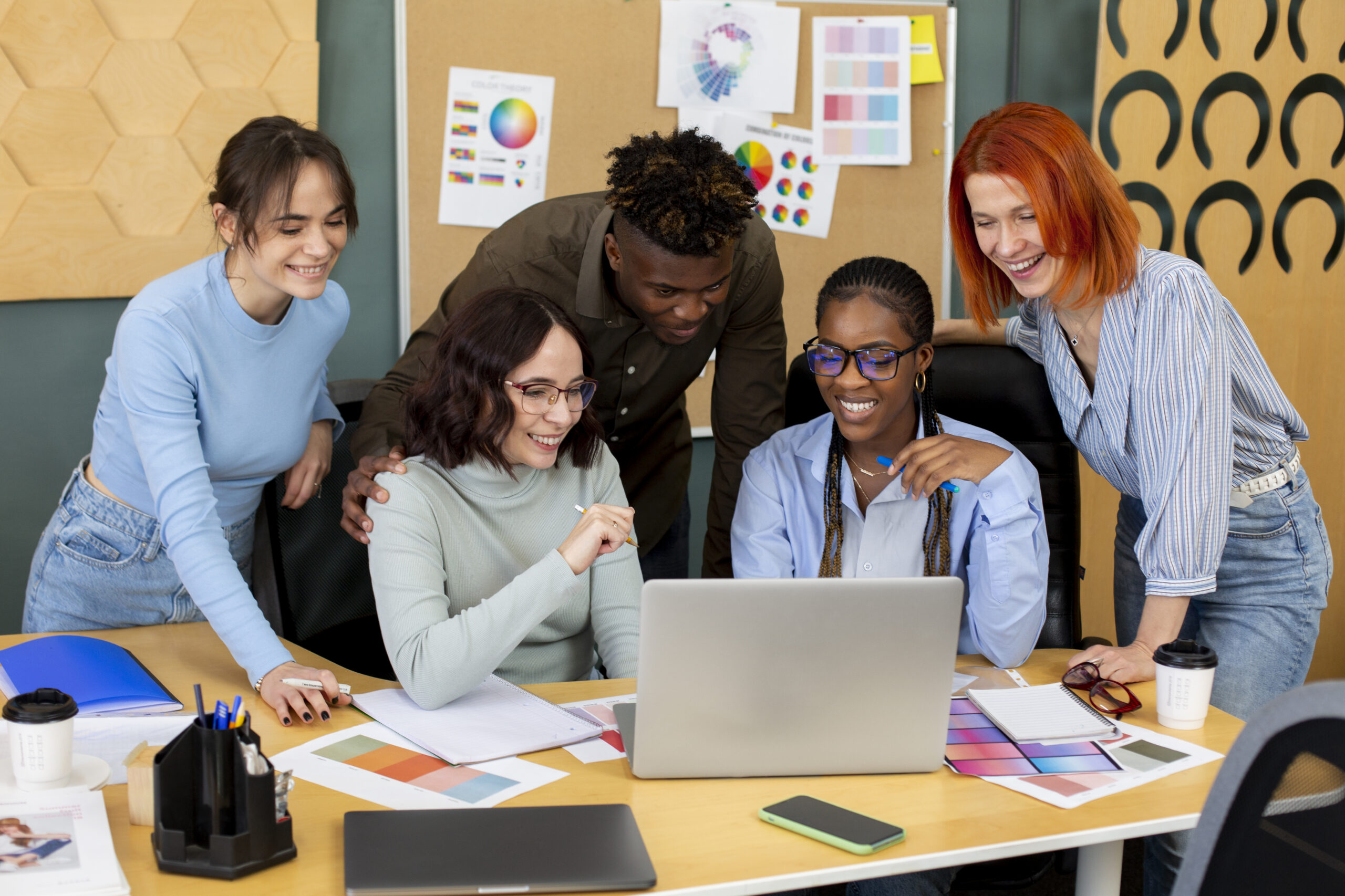 A group of smiling students looking together at a laptop screen.
